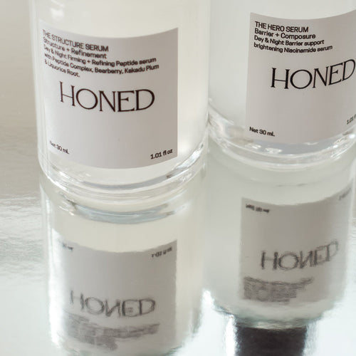 Peptide serum and niacinamide serum with a HONED label in glass bottles with a silver background
